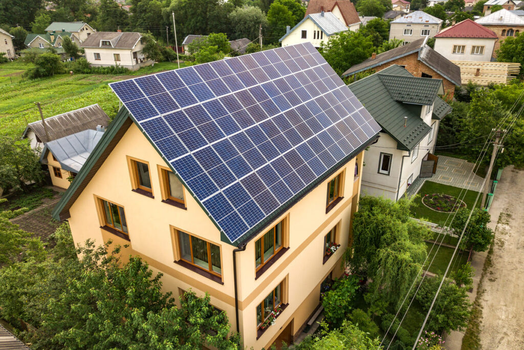 una casa con jardin y con placas solares en el techo indicando como mejorar la eficiencia energetica de una vivienda