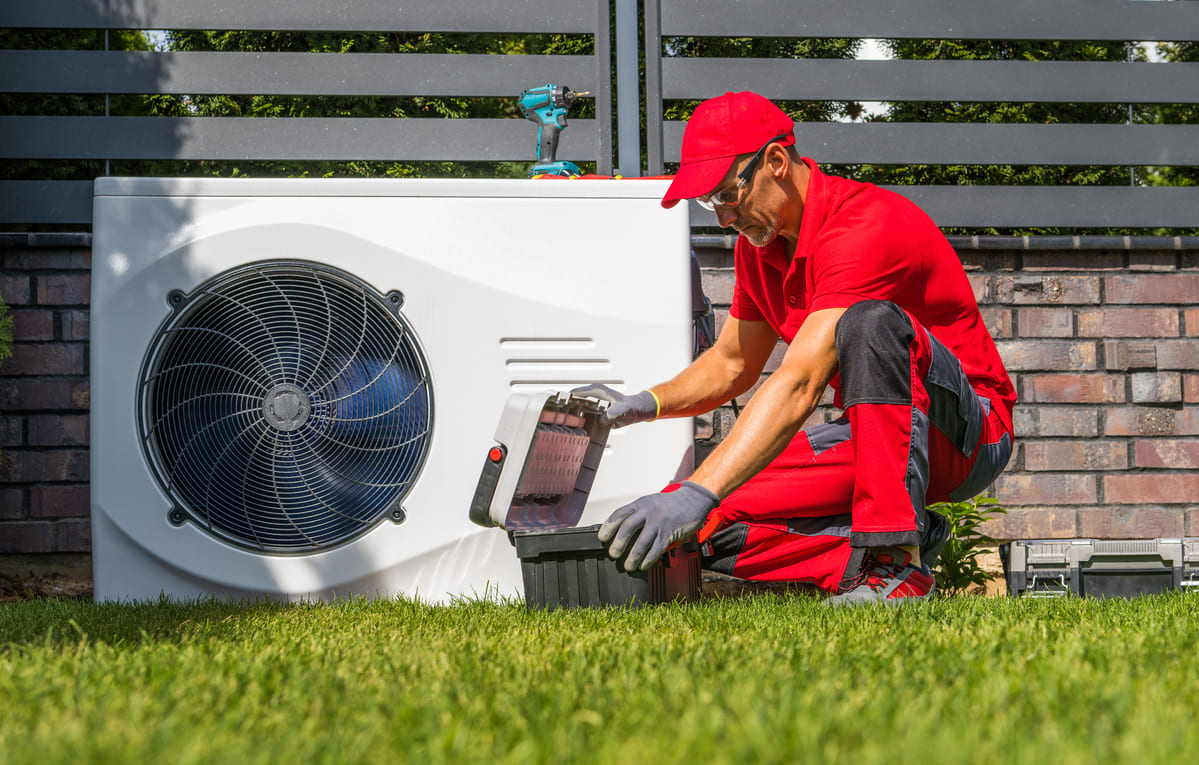 un técnico en un jardín realizando una instalación bomba de calor con aerotermia