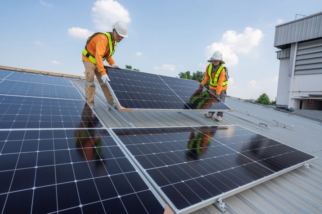 Personas portando paneles en un tejado para instalaciones solares fotovoltaicas