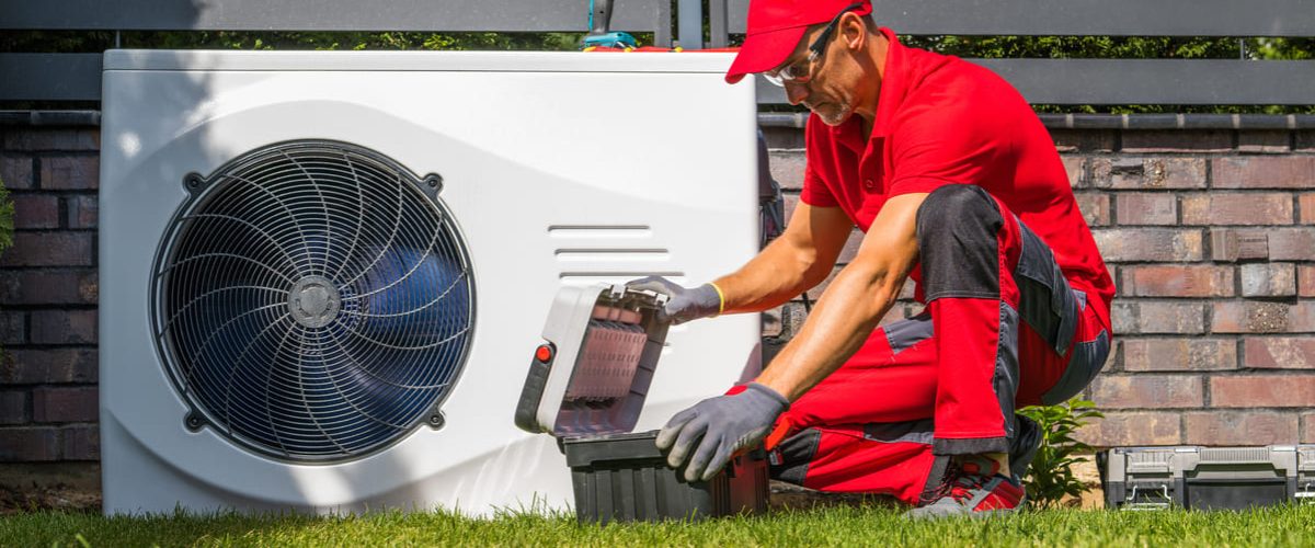 un técnico en un jardín realizando una instalación bomba de calor con aerotermia