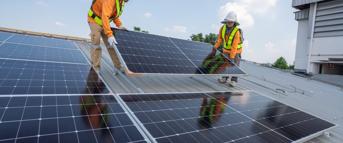 Personas portando paneles en un tejado para instalaciones solares fotovoltaicas